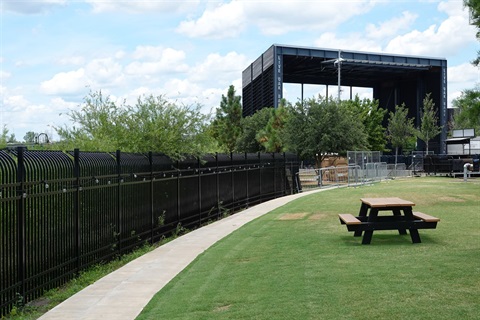 a park with a stage surrounded by a decorative fence